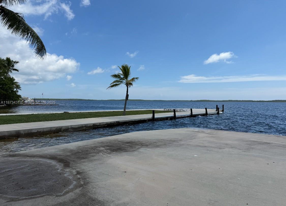 A concrete boat ramp leads to a long dock extending into a calm bay — 53 Bonefish Ave, Key Largo FL 33037, KEY LARGO, FL