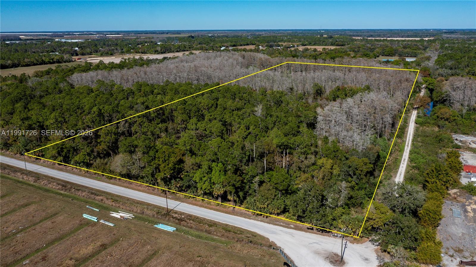 An aerial view shows a rectangular plot of wooded land bordered by a paved road — 900 G RD, La Belle FL 33935, LA BELLE, FL