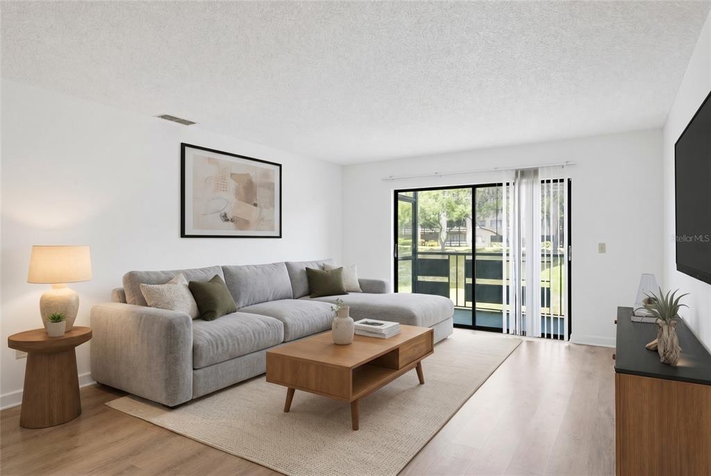 A living room features a gray sectional sofa, a wooden coffee table, and a sliding glass door — 6070 80TH STREET N UNIT 109, ST PETERSBURG, FL