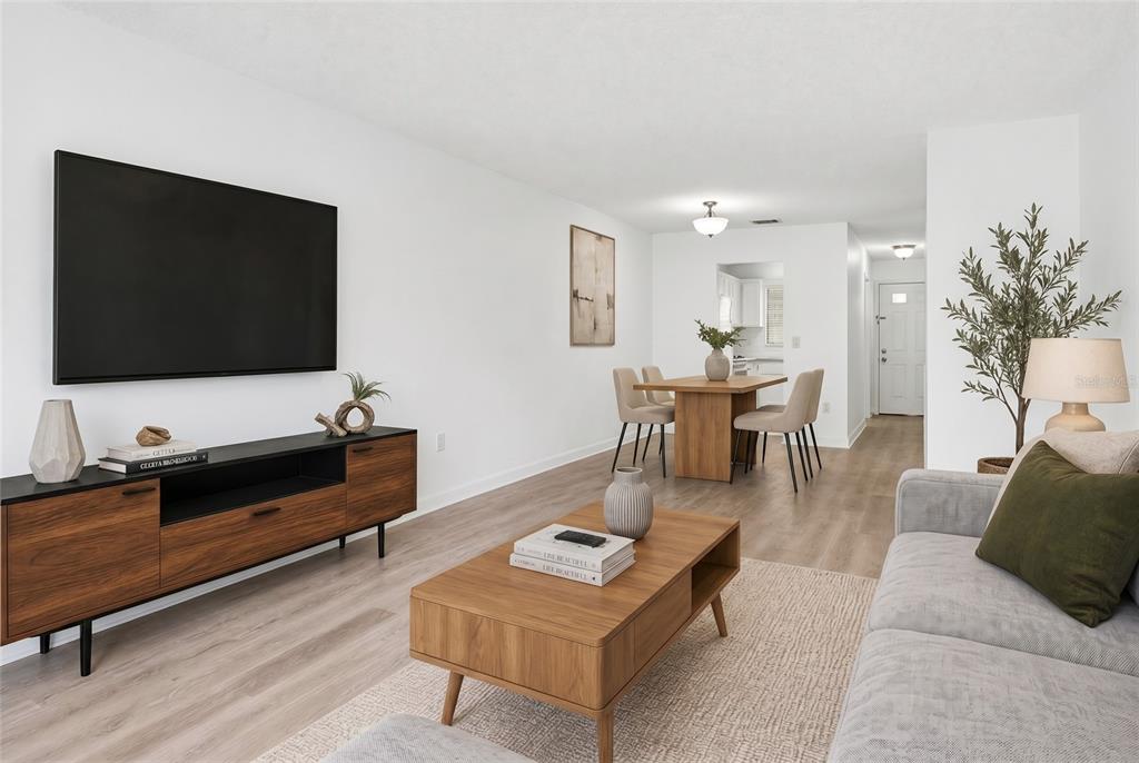 A living room with wood-look flooring, a television, a coffee table, and a dining area — 6070 80TH STREET N UNIT 109, ST PETERSBURG, FL