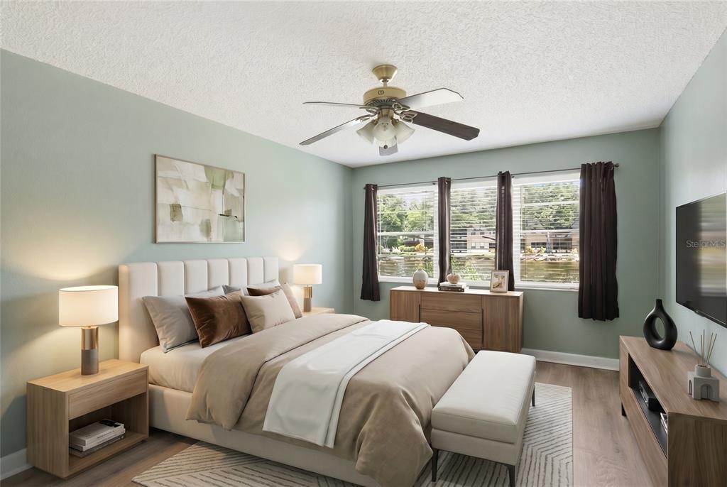 A bedroom with a bed, nightstands, a dresser, a ceiling fan, and a view of water — 6070 80TH STREET N UNIT 109, ST PETERSBURG, FL