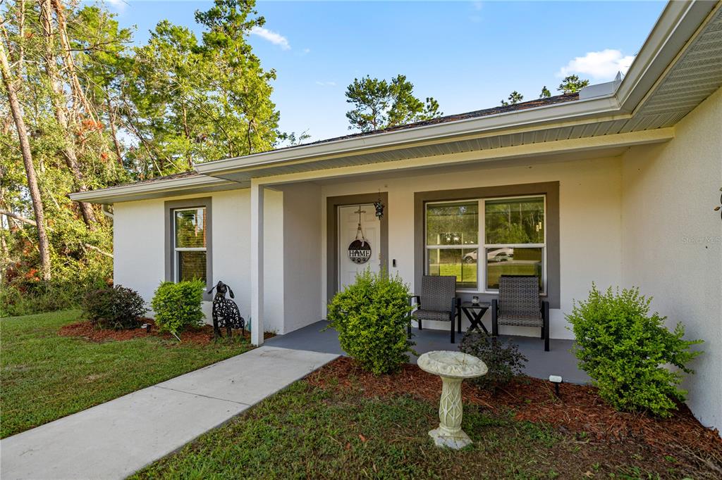 The exterior of a single-story house features a covered front porch with two chairs — 8607 SW 135TH STREET ROAD, OCALA, FL
