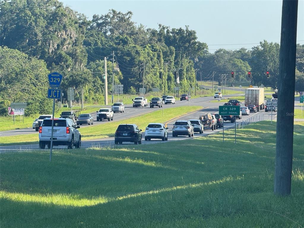 A view of a multi-lane road with traffic, a junction sign, and surrounding trees — TBD N US HIGHWAY 441, CITRA, FL