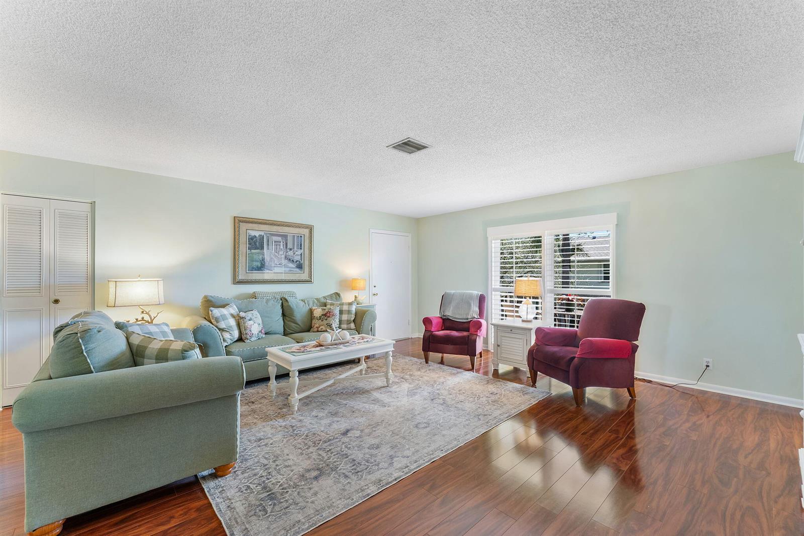 A living room features light green walls, hardwood floors, a patterned rug, and upholstered furniture — 2015 S Seacrest Boulevard # C, Boynton Beach FL 33435, BOYNTON BEACH, FL