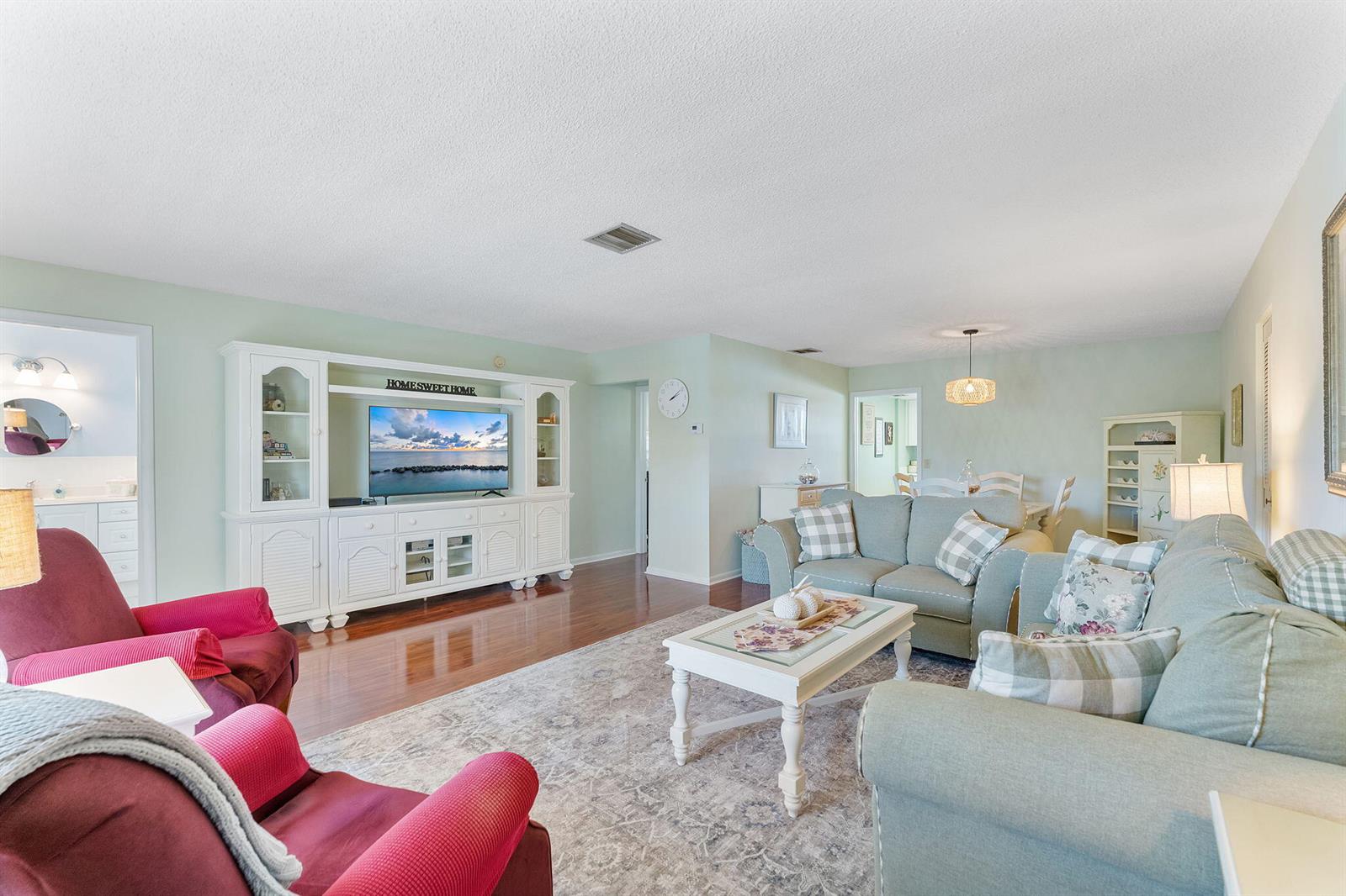 A living room features a white entertainment center, light green walls, and two red armchairs — 2015 S Seacrest Boulevard # C, Boynton Beach FL 33435, BOYNTON BEACH, FL