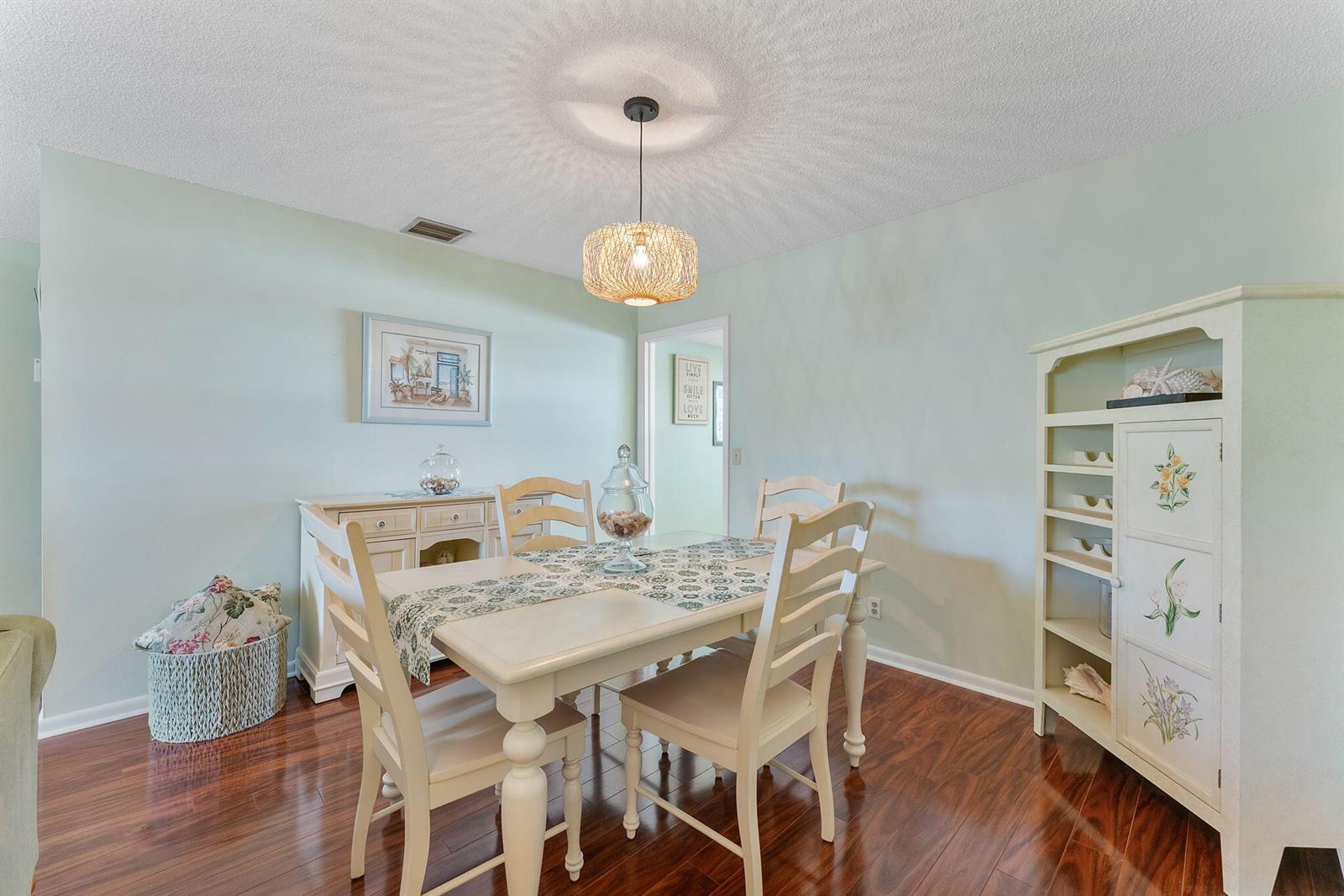 A dining room features a white table and chairs, a sideboard, and a woven pendant light — 2015 S Seacrest Boulevard # C, Boynton Beach FL 33435, BOYNTON BEACH, FL