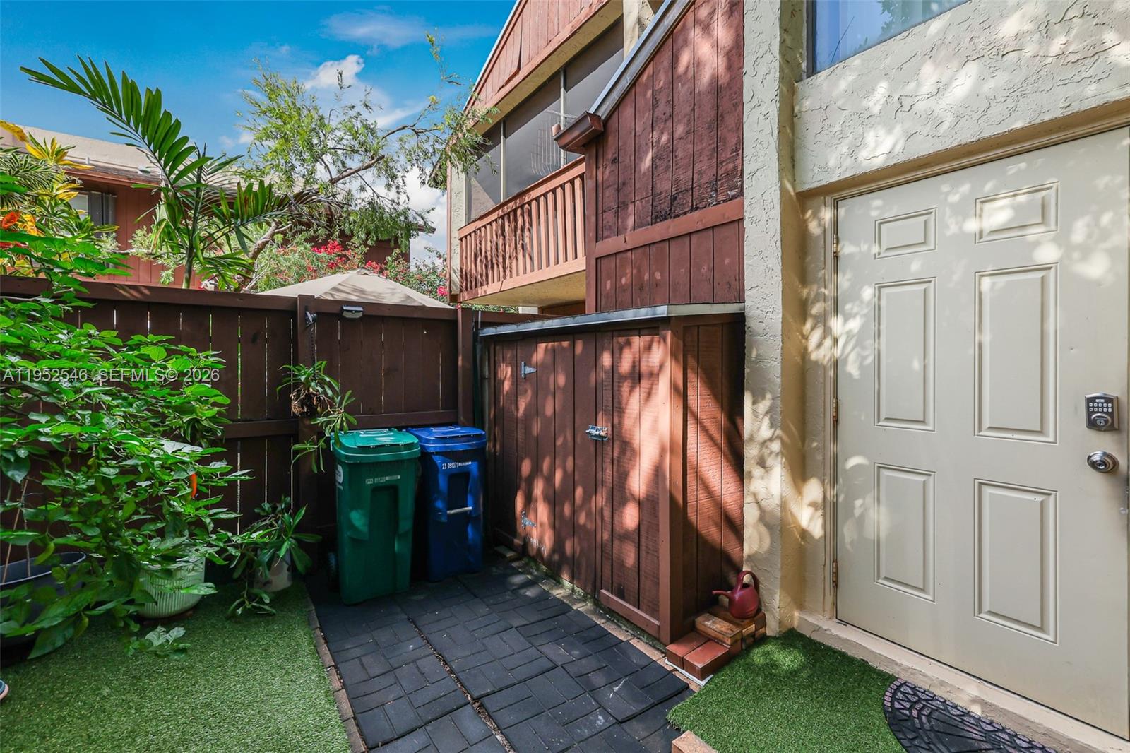 A patio area features a wooden storage shed, two trash bins, and a white door — 7014 SW 114th Pl # C53, Miami FL 33173, MIAMI, FL