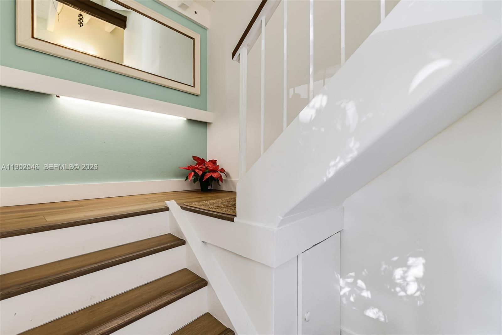 A staircase with wooden treads and white risers leads to a landing with a mirror — 7014 SW 114th Pl # C53, Miami FL 33173, MIAMI, FL