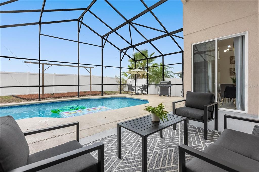 A screened-in patio features a swimming pool, outdoor seating, and a grill in the backyard — 638 CASSIA DRIVE, DAVENPORT, FL