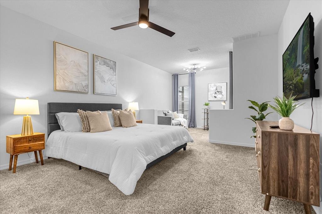 A spacious bedroom features a king bed, a sitting area, and a wall-mounted television — 638 CASSIA DRIVE, DAVENPORT, FL