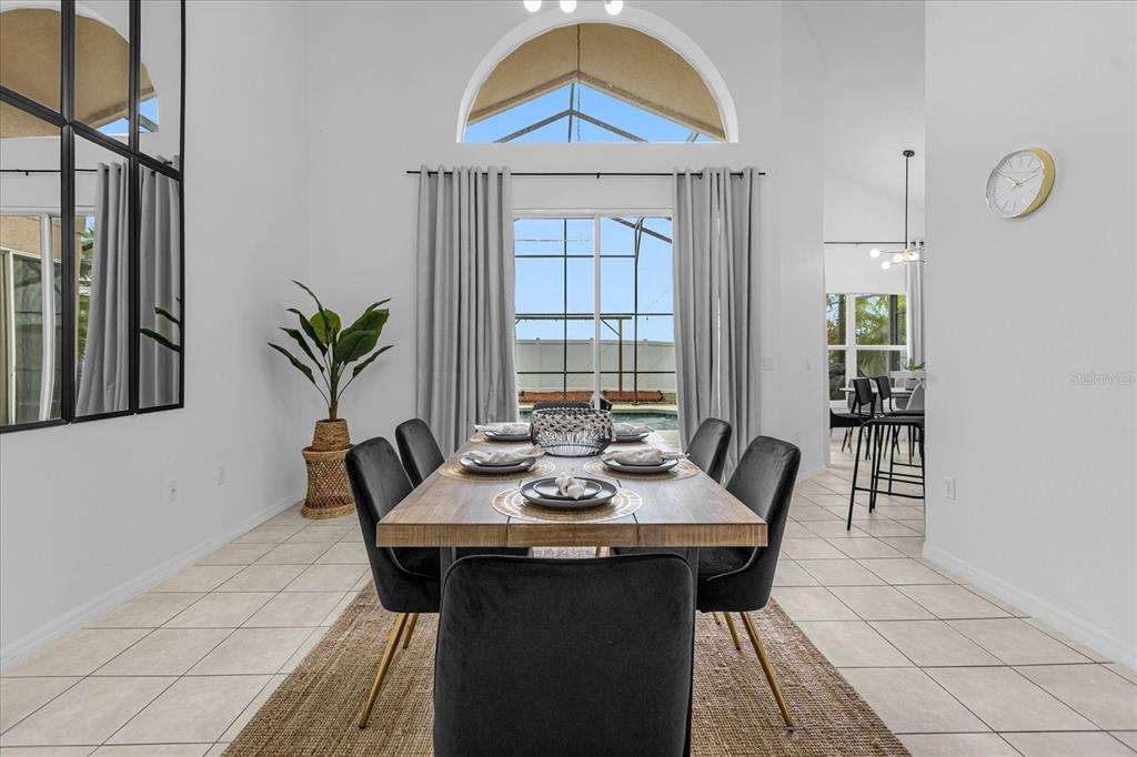A dining room features a wooden table, black chairs, tile flooring, and a pool view — 638 CASSIA DRIVE, DAVENPORT, FL