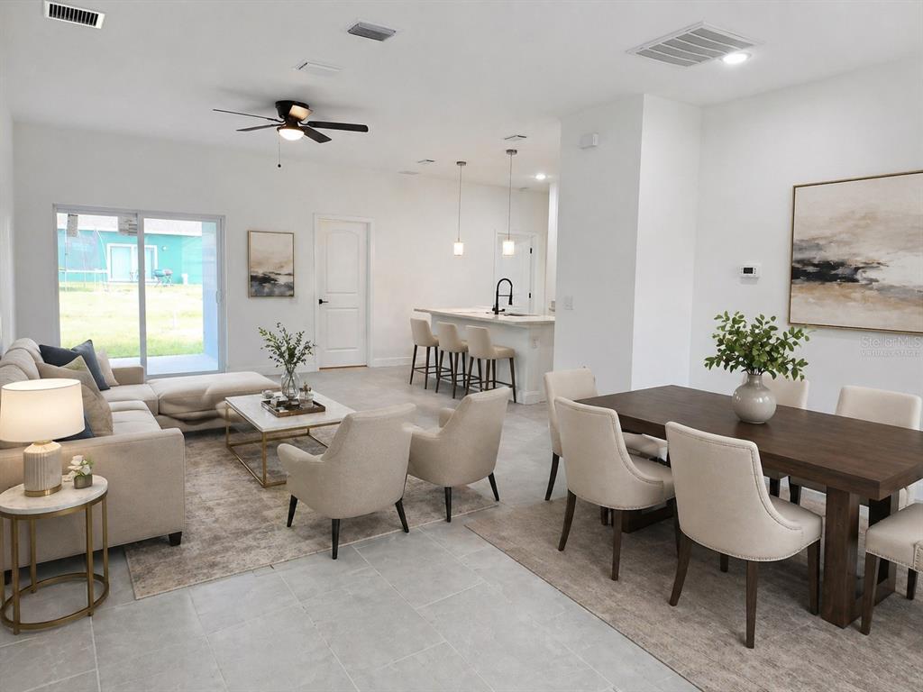 This open-concept living and dining area features tile flooring, neutral furniture, and a kitchen island — 415 TONKLIN ROAD SW, PALM BAY, FL
