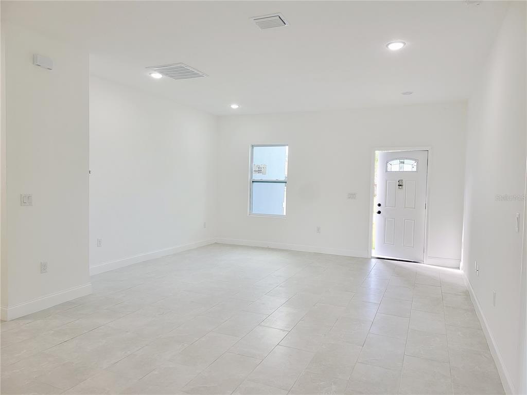 An empty room with white walls, tiled floors, a single window, and a front door — 415 TONKLIN ROAD SW, PALM BAY, FL
