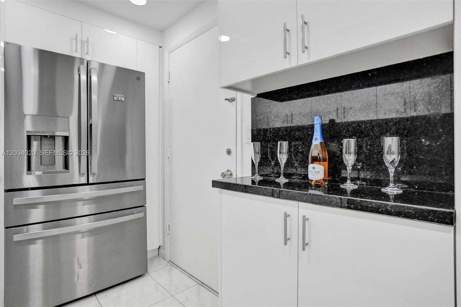 A kitchen features white cabinets, stainless steel appliances, and a black granite countertop — 1849 S Ocean Dr # 407, Hallandale Beach FL 33009, HALLANDALE BEACH, FL