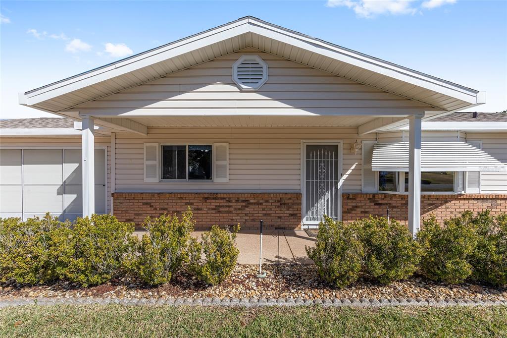 A single-story house with beige siding, a brick base, and a covered front porch — 17929 SE 104TH TERRACE, SUMMERFIELD, FL