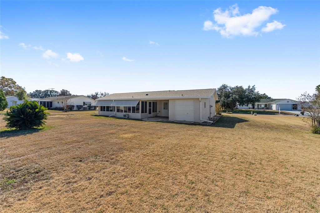 A light-colored single-story house with a screened-in porch and attached garage sits on a lawn — 17929 SE 104TH TERRACE, SUMMERFIELD, FL