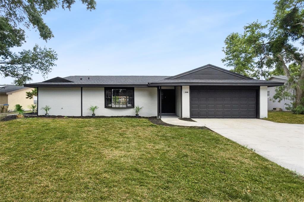 A single-story house with white stucco walls, a dark roof, and a two-car garage — 2661 ELLEN AVENUE, KISSIMMEE, FL