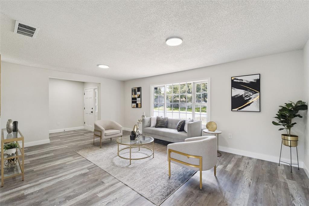 A living room features gray wood-look flooring, a gray sofa, two armchairs, and a rug — 2661 ELLEN AVENUE, KISSIMMEE, FL