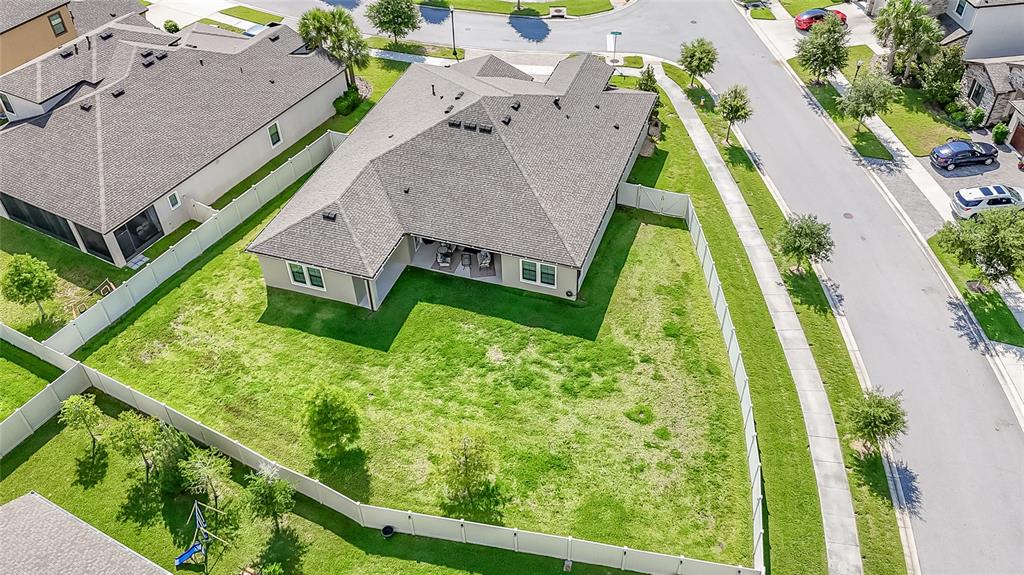 An aerial view of a single-story house with a large fenced backyard and corner lot — 8687 BIRCHLEAF COURT COURT, LAND O LAKES, FL