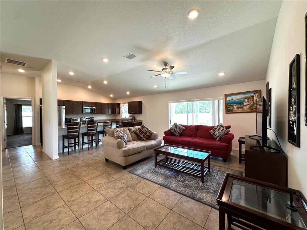The backyard features a grassy lawn, a white vinyl fence, and a concrete patio area — 15211 SW 65TH TERRACE ROAD, OCALA, FL