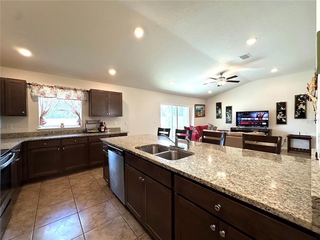 A living room features tile flooring, a ceiling fan, a television console, and a sofa — 15211 SW 65TH TERRACE ROAD, OCALA, FL