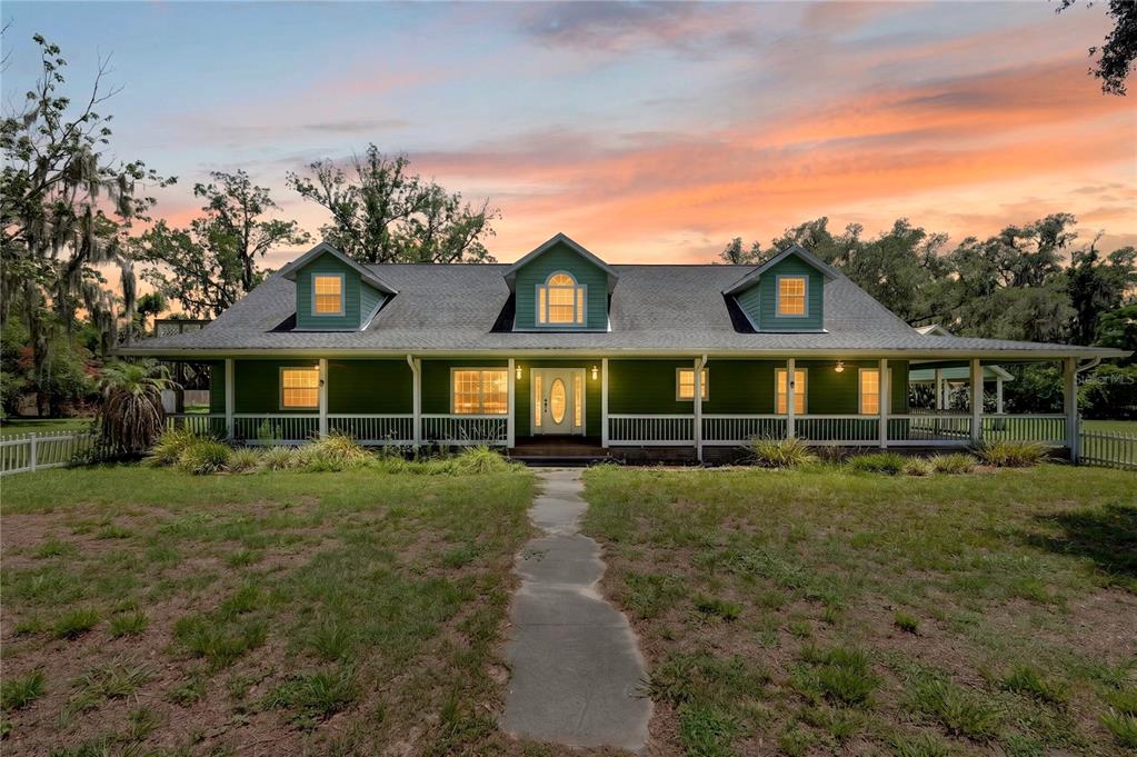 A green, single-story house with a wrap-around porch and three dormer windows at sunset — 2039 SW STATE ROAD 26, TRENTON, FL