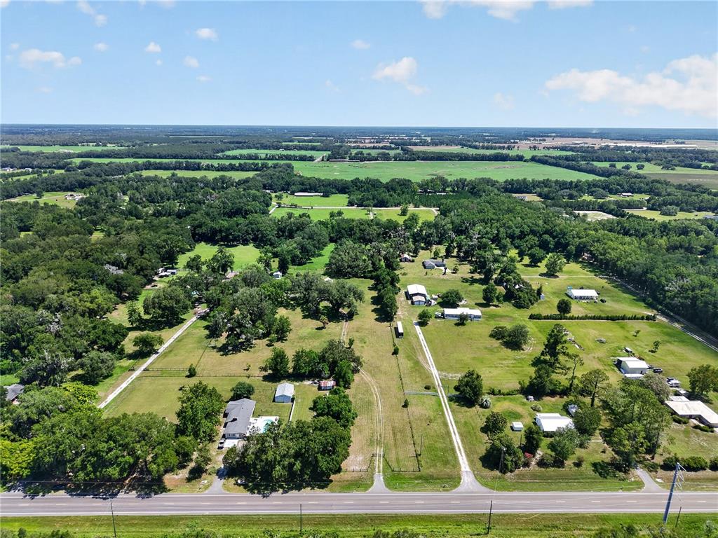An aerial view shows several houses and outbuildings situated on large, grassy, tree-lined rural lots — 2039 SW STATE ROAD 26, TRENTON, FL