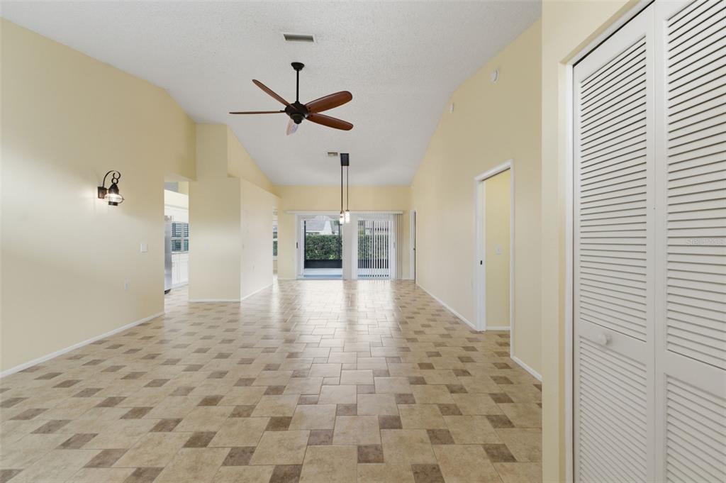 A spacious room with light yellow walls, tiled floors, a ceiling fan, and sliding doors — 6525 PINE WALK DRIVE, NEW PORT RICHEY, FL