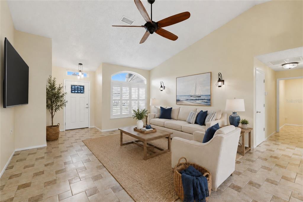 A living room features tile flooring, a vaulted ceiling with a fan, and neutral furniture — 6525 PINE WALK DRIVE, NEW PORT RICHEY, FL