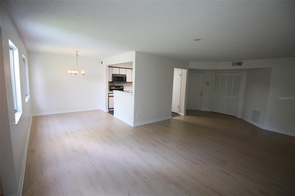 An open-concept living and dining area features light wood-look flooring and a pass-through kitchen — 5301 WHITE CLIFF LANE UNIT 2, ORLANDO, FL