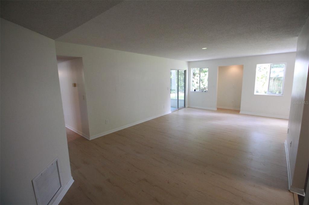 An empty living room features light wood-look flooring, white walls, and a sliding glass door — 5301 WHITE CLIFF LANE UNIT 2, ORLANDO, FL