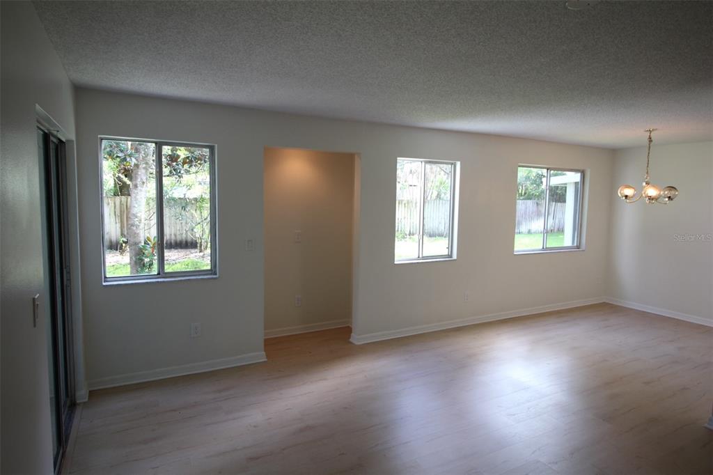 A bright living area features light wood-look flooring, white walls, and three windows — 5301 WHITE CLIFF LANE UNIT 2, ORLANDO, FL