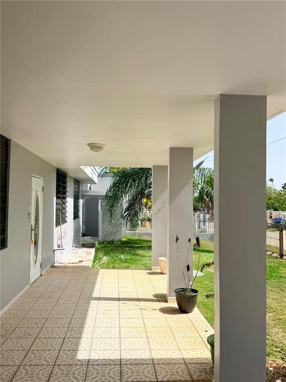 A covered outdoor patio features light-colored patterned tile flooring and gray support columns — #131 CALLE HARRINSON BASE RAMEY, AGUADILLA, PR