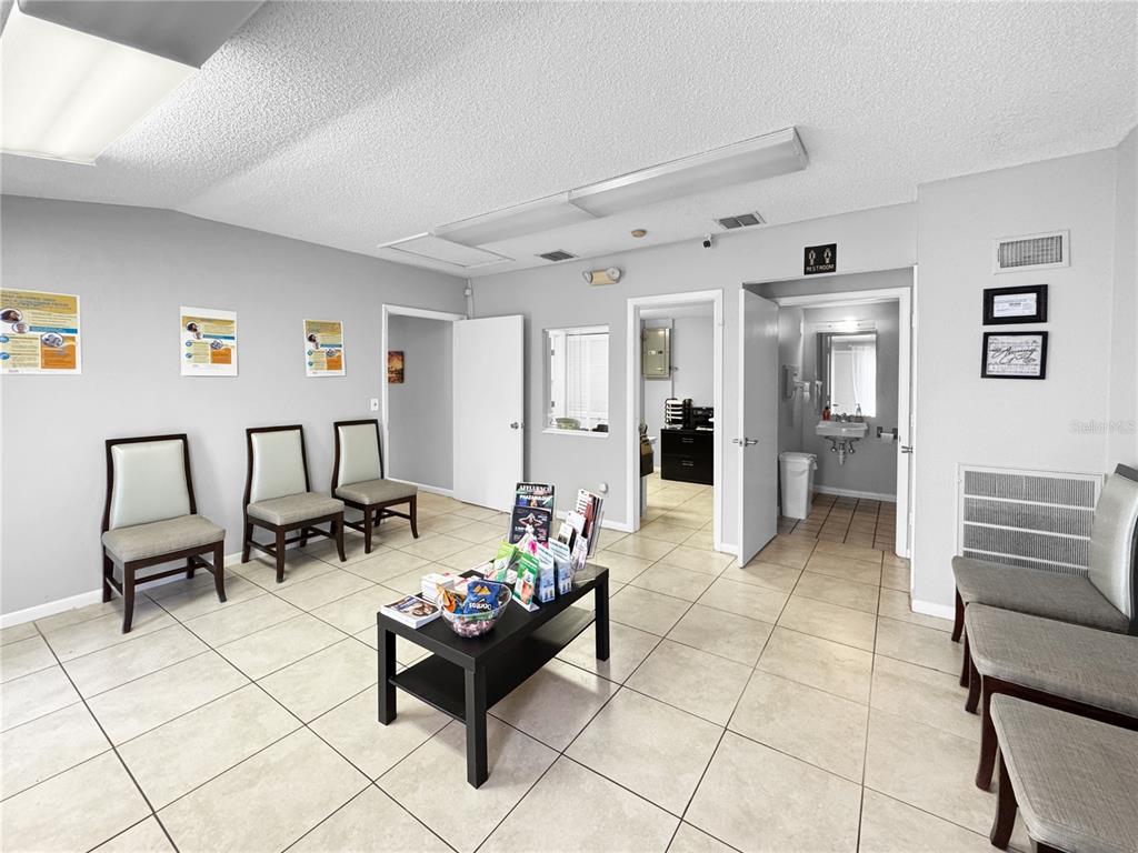 A waiting room features tile flooring, several chairs, a central table, and two open doorways — 5438 TROUBLE CREEK ROAD, NEW PORT RICHEY, FL