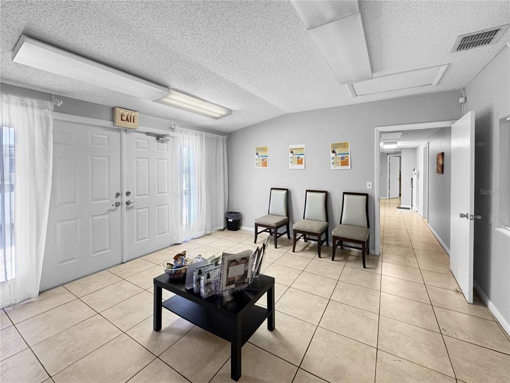 A waiting room features tile flooring, three chairs, a coffee table, and double exit doors — 5438 TROUBLE CREEK ROAD, NEW PORT RICHEY, FL