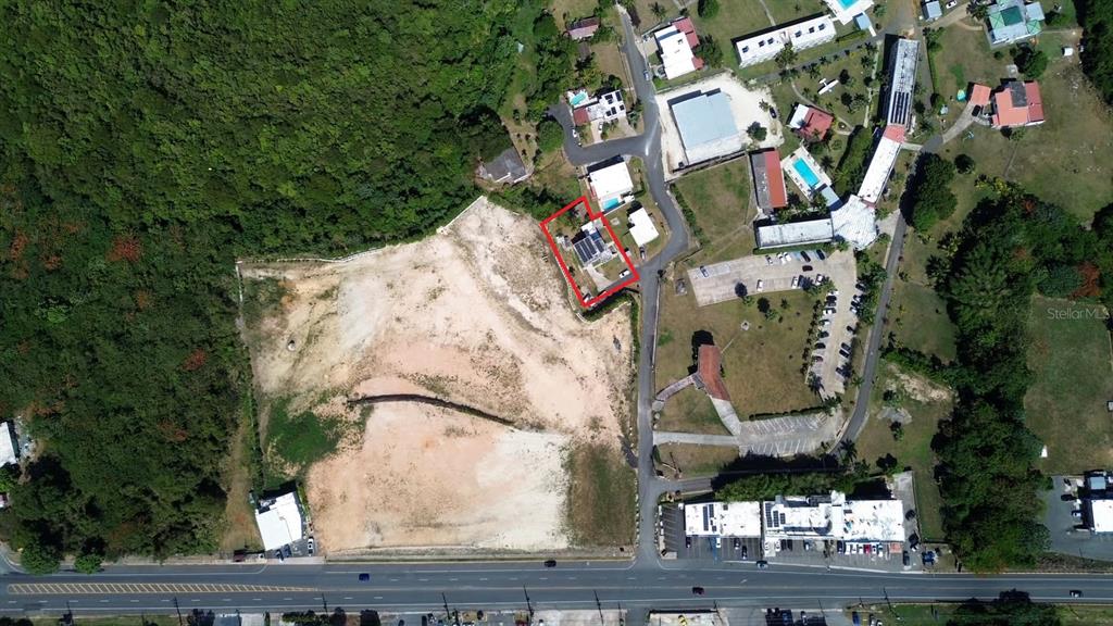 An aerial view shows a house outlined in red next to a large cleared lot — PR-107 KM 2.2 INT CALLE SAN JOSE, AGUADILLA, PR