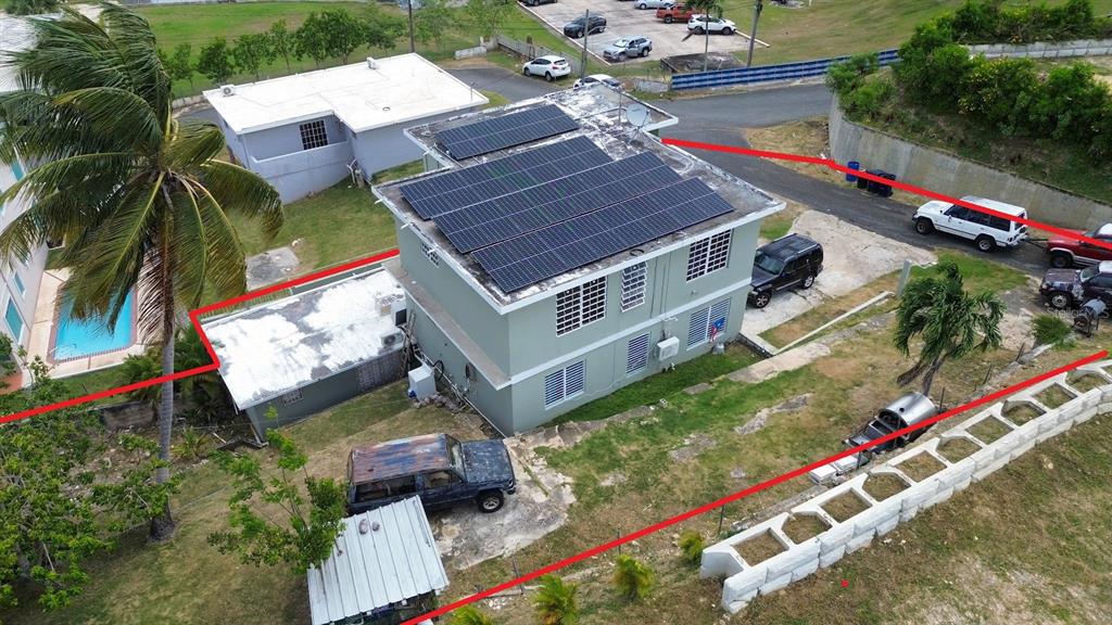 An aerial view shows a two-story house with rooftop solar panels and a detached garage — PR-107 KM 2.2 INT CALLE SAN JOSE, AGUADILLA, PR