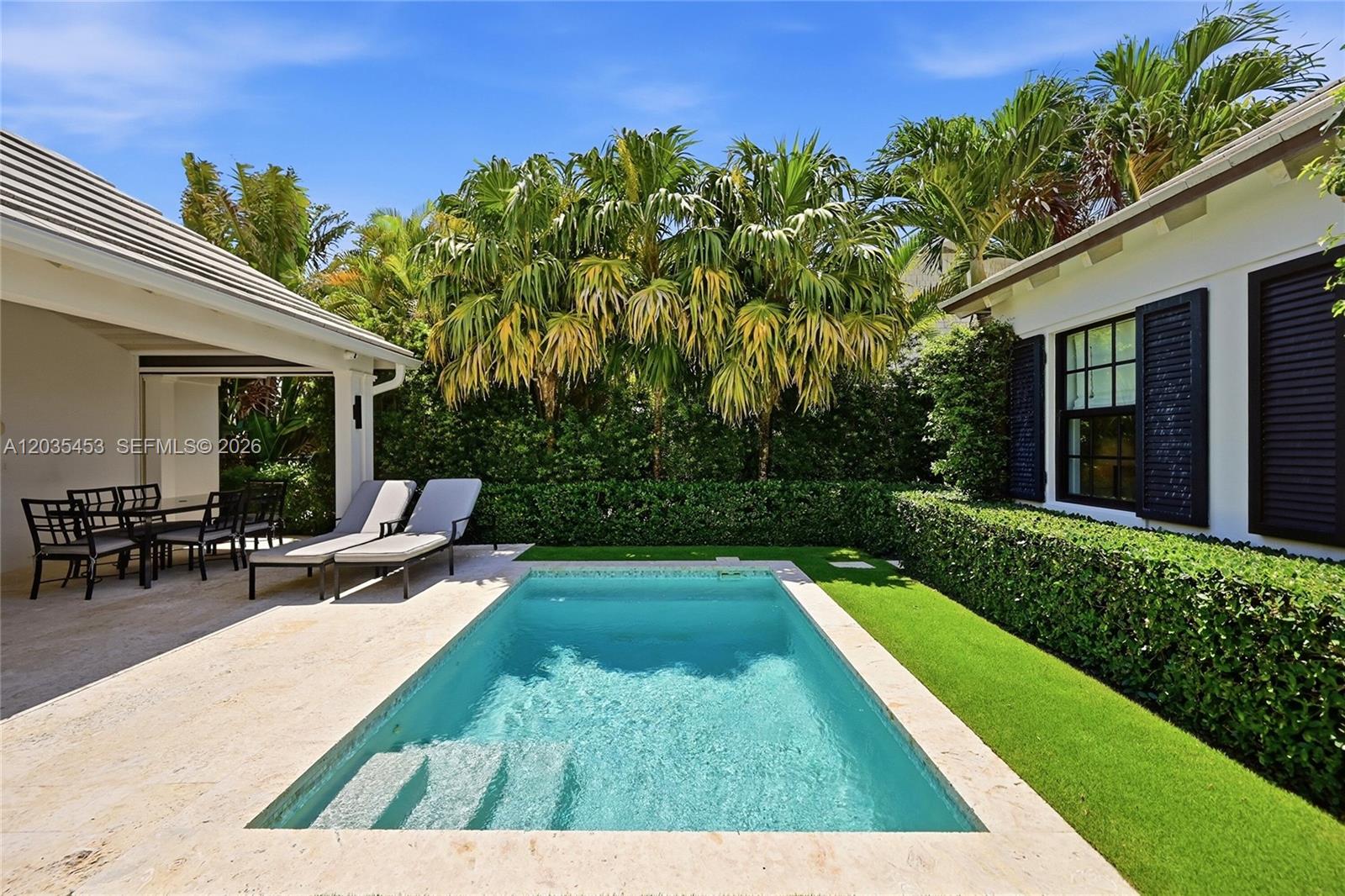 A backyard features a rectangular swimming pool, lounge chairs, a covered patio, and manicured hedges — 135 Chilean Ave, Palm Beach FL 33480, PALM BEACH, FL