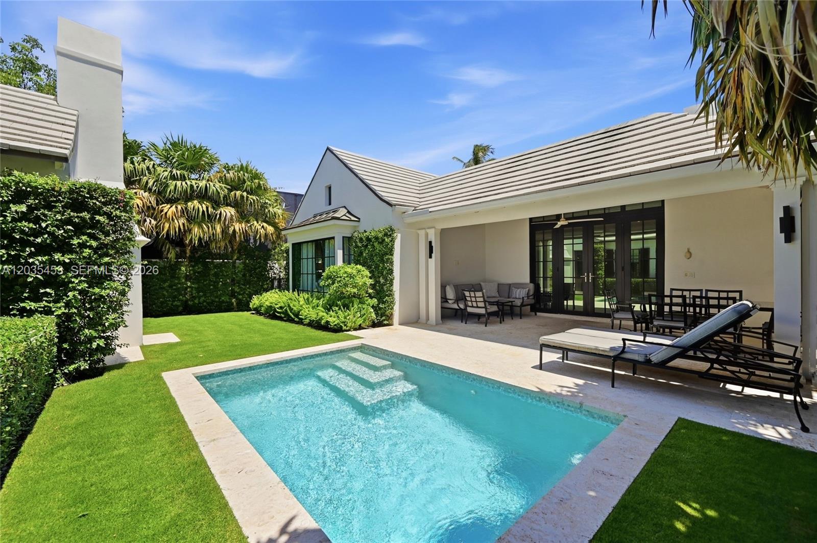 A backyard features a rectangular swimming pool, a covered patio, and a manicured lawn — 135 Chilean Ave, Palm Beach FL 33480, PALM BEACH, FL