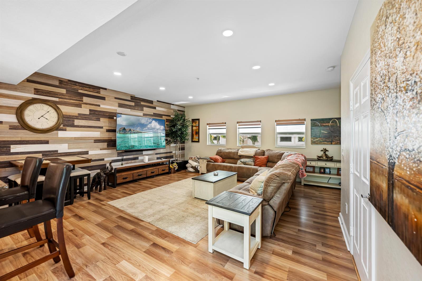 A living room features a wood-paneled accent wall, a large sectional sofa, and wood flooring — 429 NE 1st Street, Pompano Beach FL 33060, POMPANO BEACH, FL