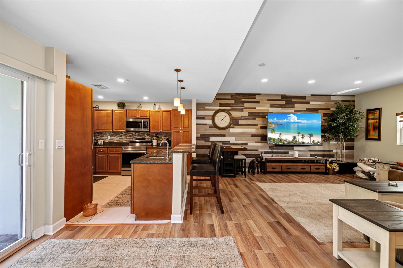 An open-concept kitchen and living area featuring wood-look flooring and a wood-paneled accent wall — 429 NE 1st Street, Pompano Beach FL 33060, POMPANO BEACH, FL