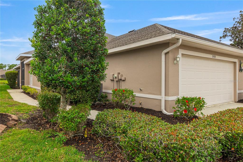 A side view of a house exterior featuring a garage, landscaping, and a walkway — 3533 LAKEWOOD BOULEVARD, NORTH PORT, FL
