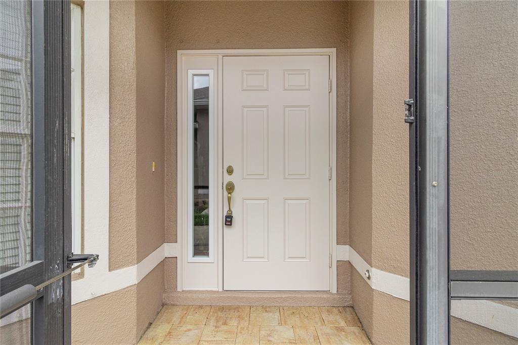 A white front door with a side window sits within a tan stucco entryway — 3533 LAKEWOOD BOULEVARD, NORTH PORT, FL