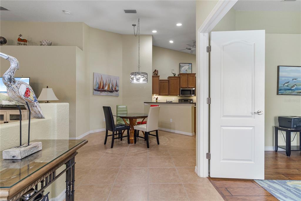 A dining area with a glass table and chairs sits between a kitchen and entryway — 3533 LAKEWOOD BOULEVARD, NORTH PORT, FL