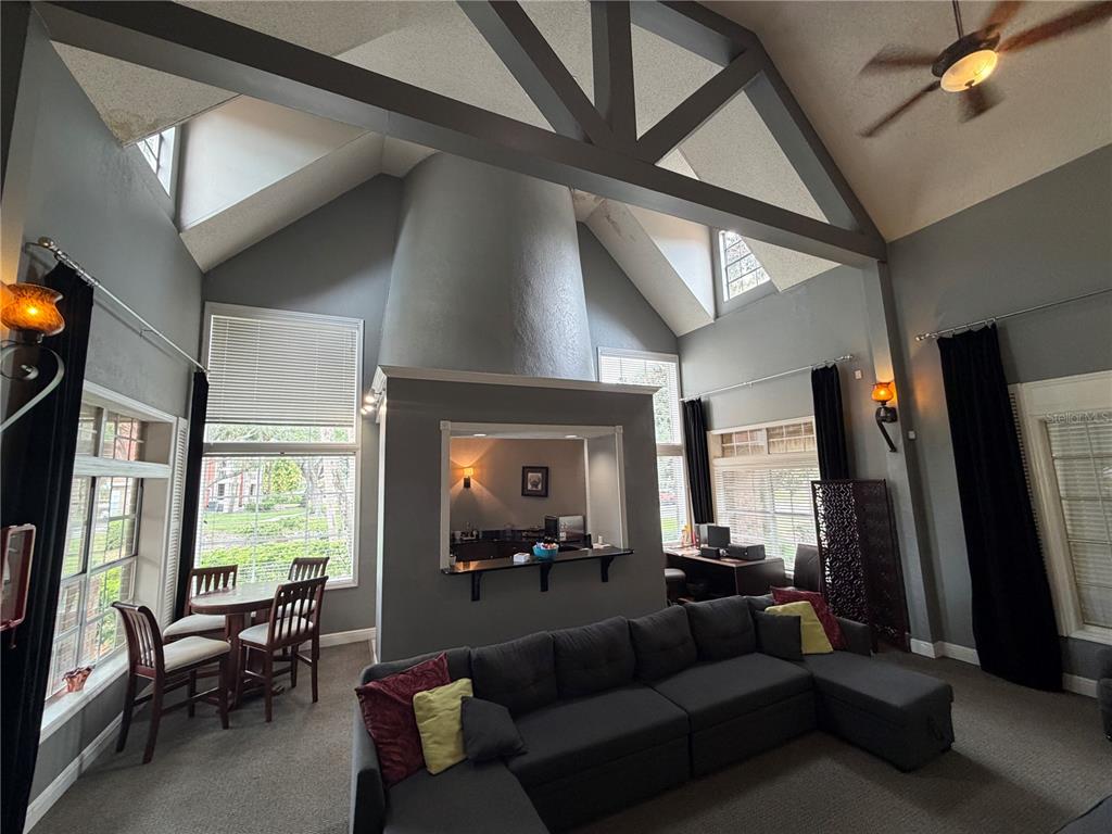 A living room with vaulted ceilings, a central fireplace, and a built-in bar area — 10200 GANDY BOULEVARD N UNIT 512, ST PETERSBURG, FL