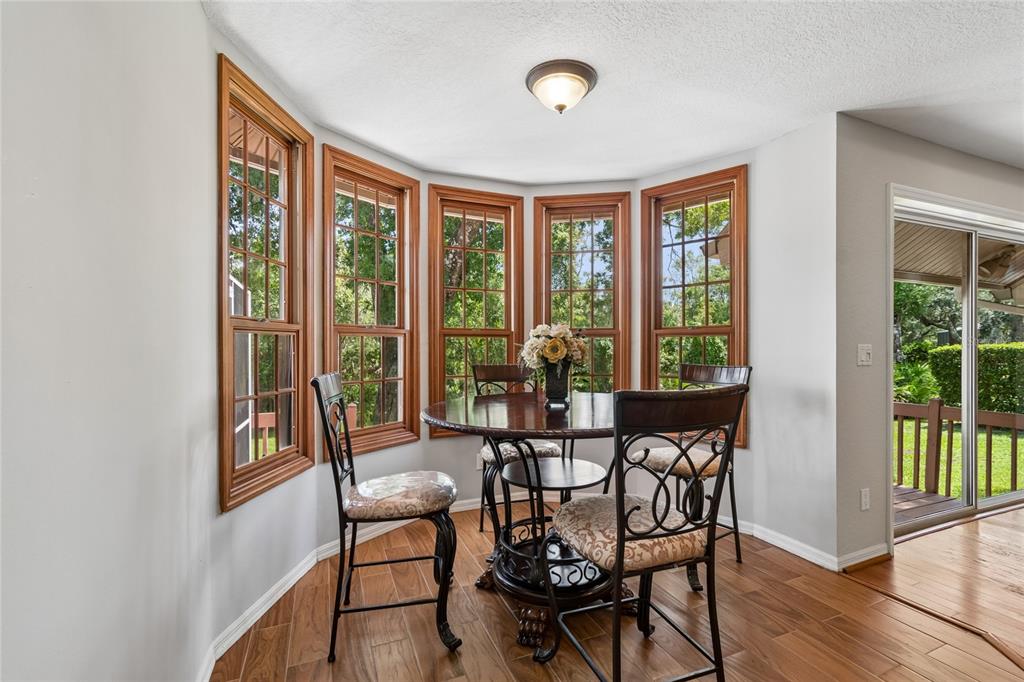 A dining area features a round table, four chairs, and a bay window with wood trim — 1055 RIVERSIDE RIDGE ROAD, TARPON SPRINGS, FL
