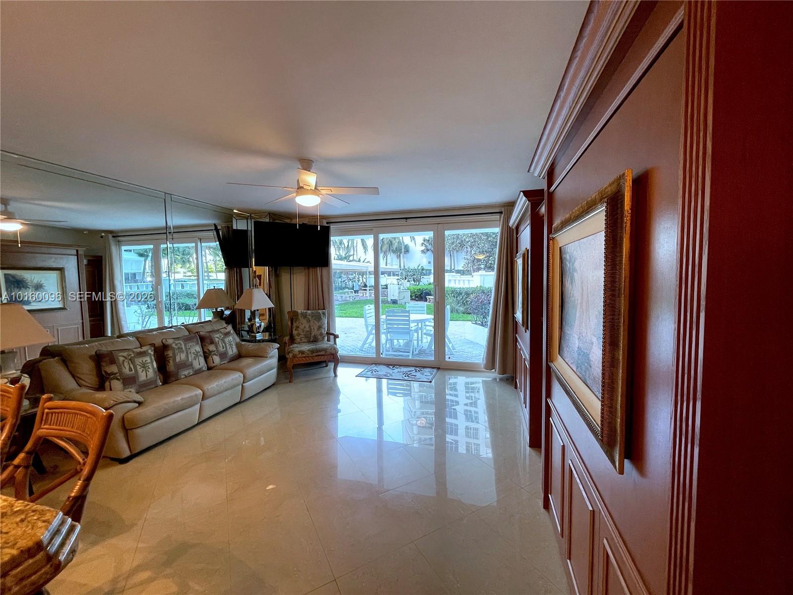 A living room features beige tile floors, a tan sofa, and glass doors leading outside — 3505 S Ocean Dr # 105, Hollywood FL 33019, HOLLYWOOD, FL