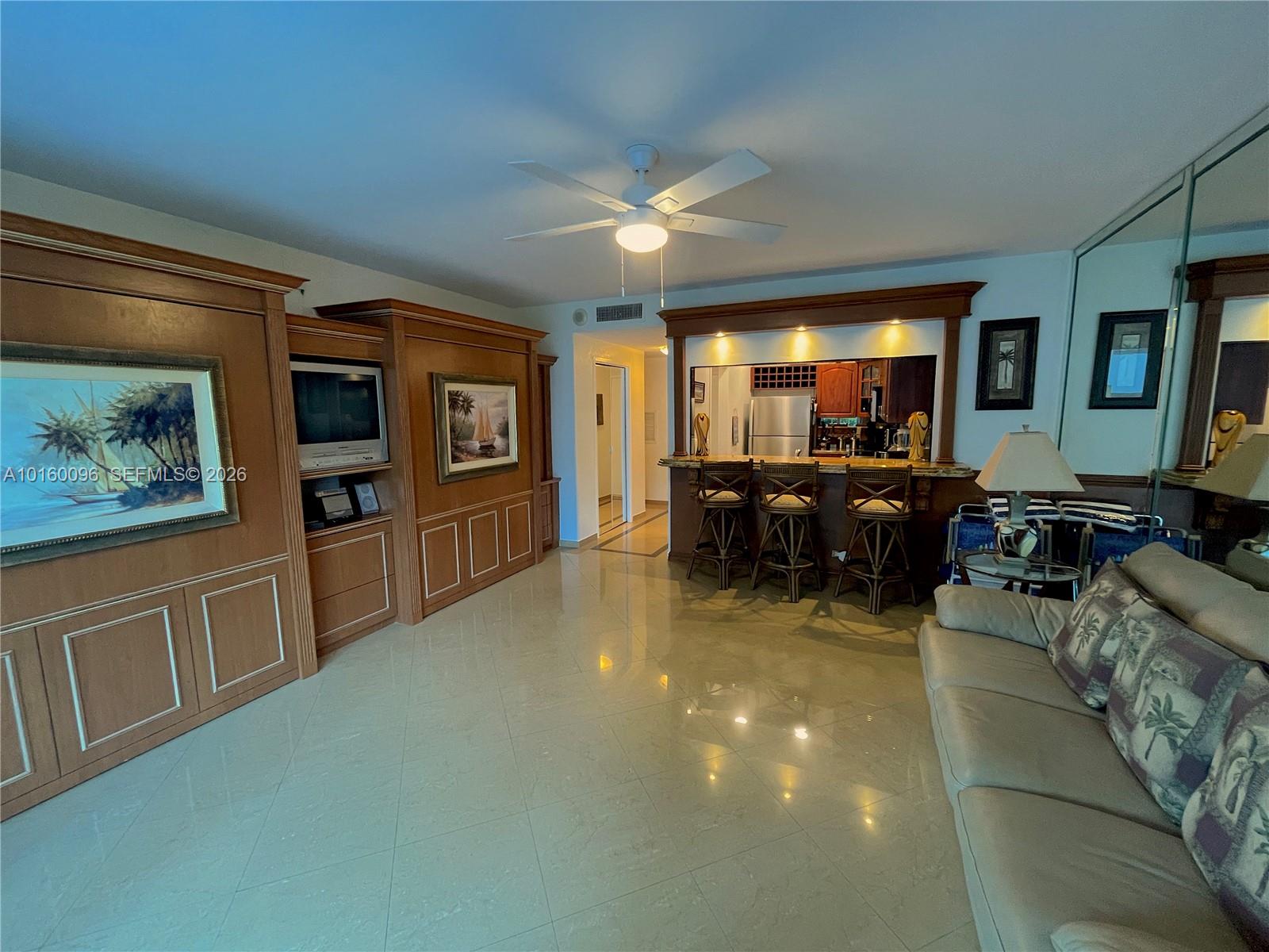 A living room features tile floors, a built-in entertainment center, and a kitchen breakfast bar — 3505 S Ocean Dr # 105, Hollywood FL 33019, HOLLYWOOD, FL