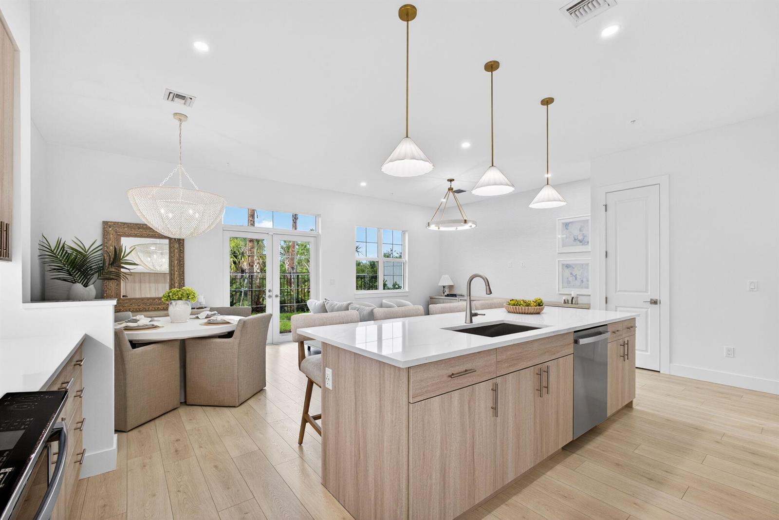 A modern kitchen with light wood cabinets, a white island, and an adjacent dining area — 115 Water Pointe Place # 35, Jupiter FL 33477, JUPITER, FL