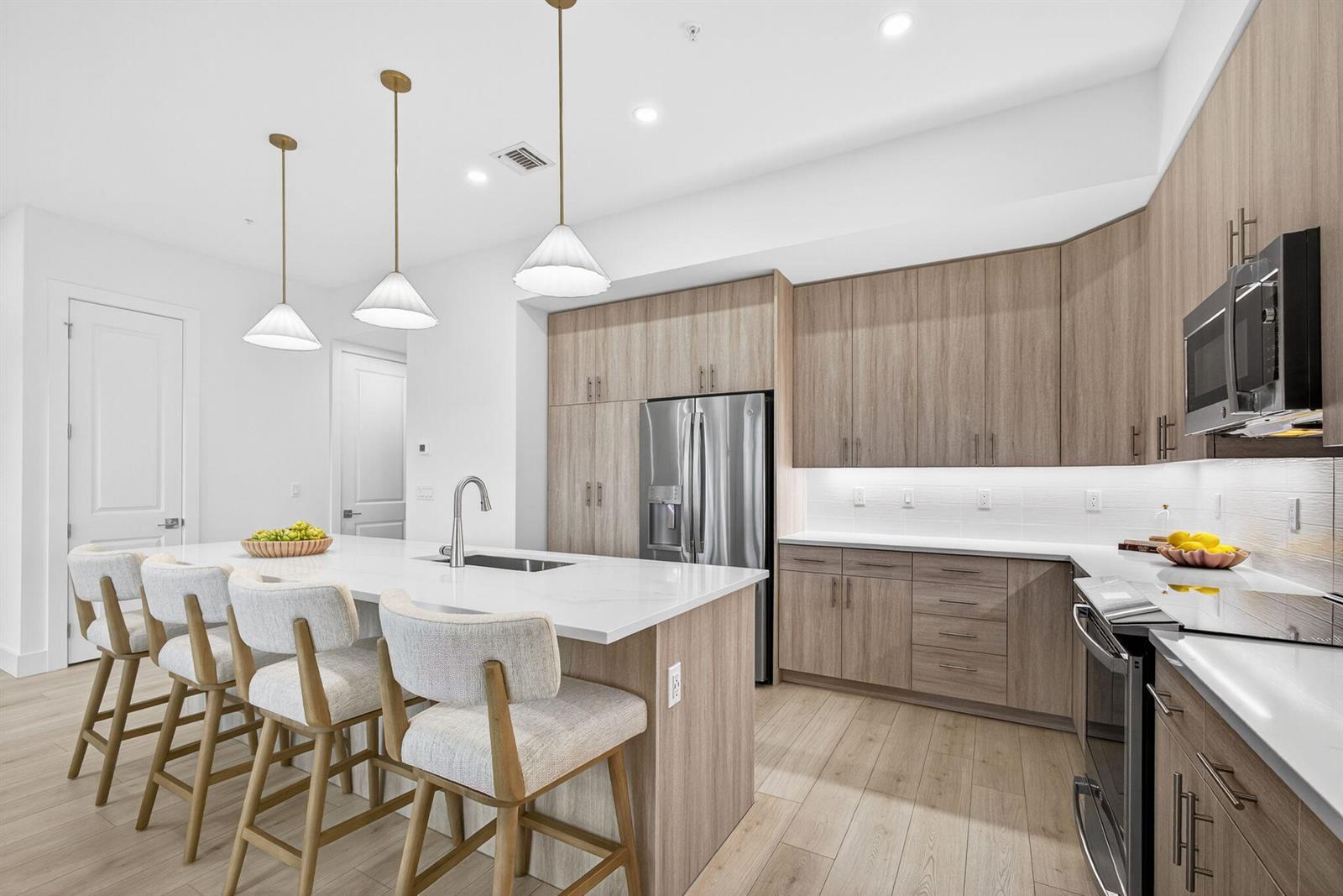 A modern kitchen features light wood cabinets, a white quartz island, and three pendant lights — 115 Water Pointe Place # 35, Jupiter FL 33477, JUPITER, FL